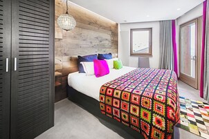 Una camera da letto moderna con una testiera in legno, una coperta colorata e un'ampia finestra con tende.