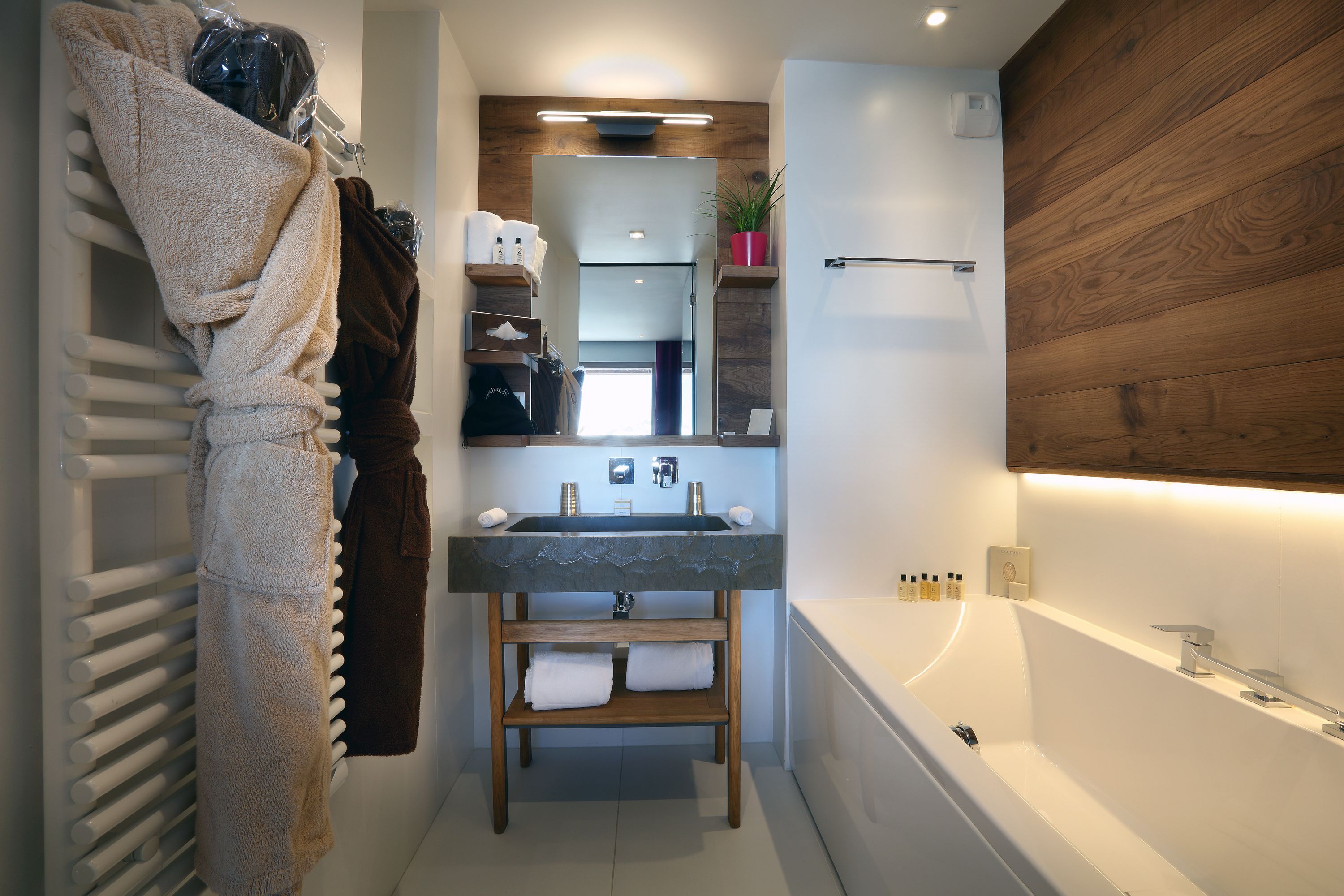 A modern bathroom with a built-in sink, a wooden vanity, a towel rack, and a bathtub.