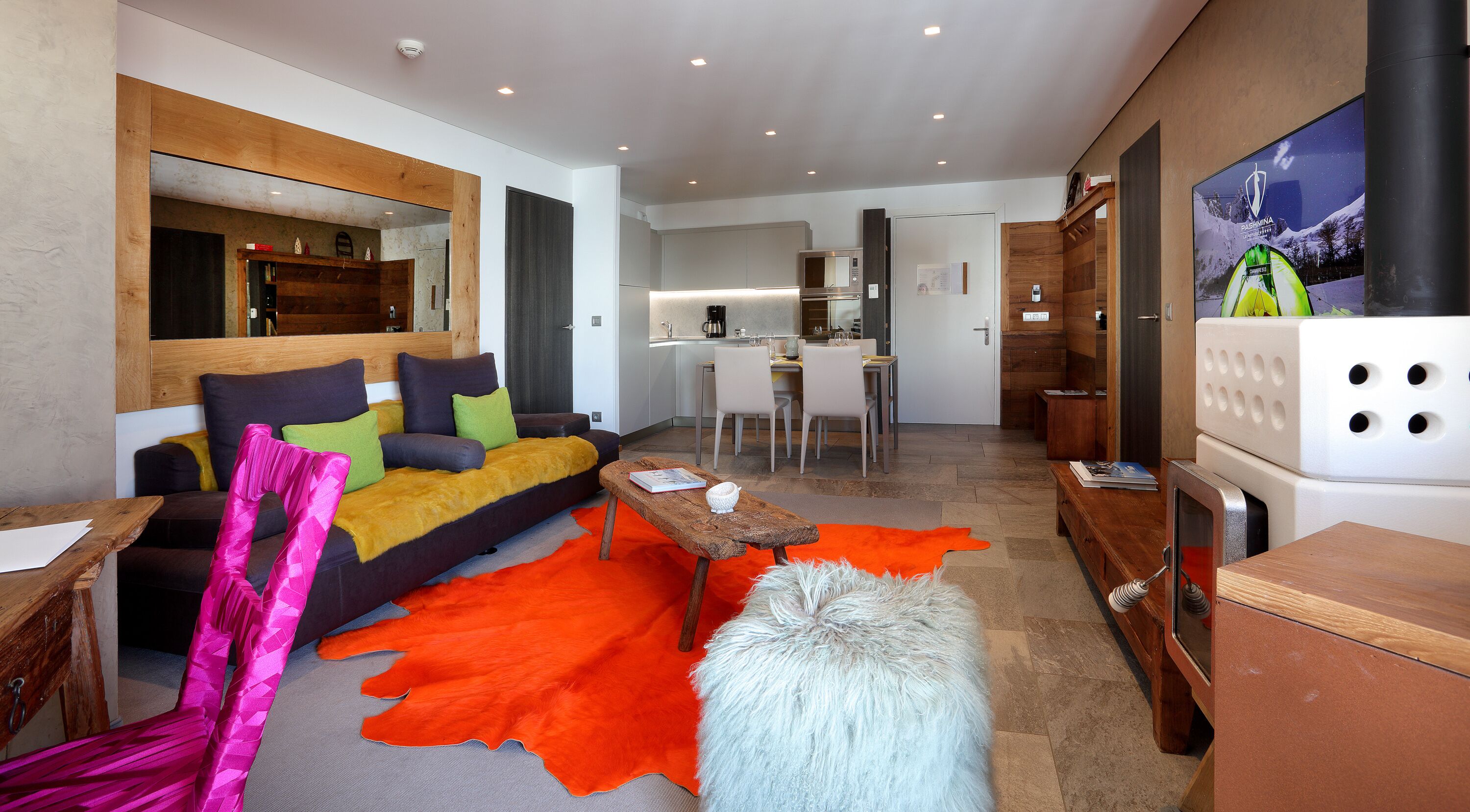 A modern living room with a sofa, coffee table, and a vibrant orange rug.