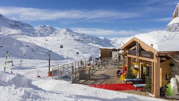 Ein schneebedecktes Bergresort mit einem Holzbauten, einer Seilbahn und einem roten Teppich, der zum Eingang führt.