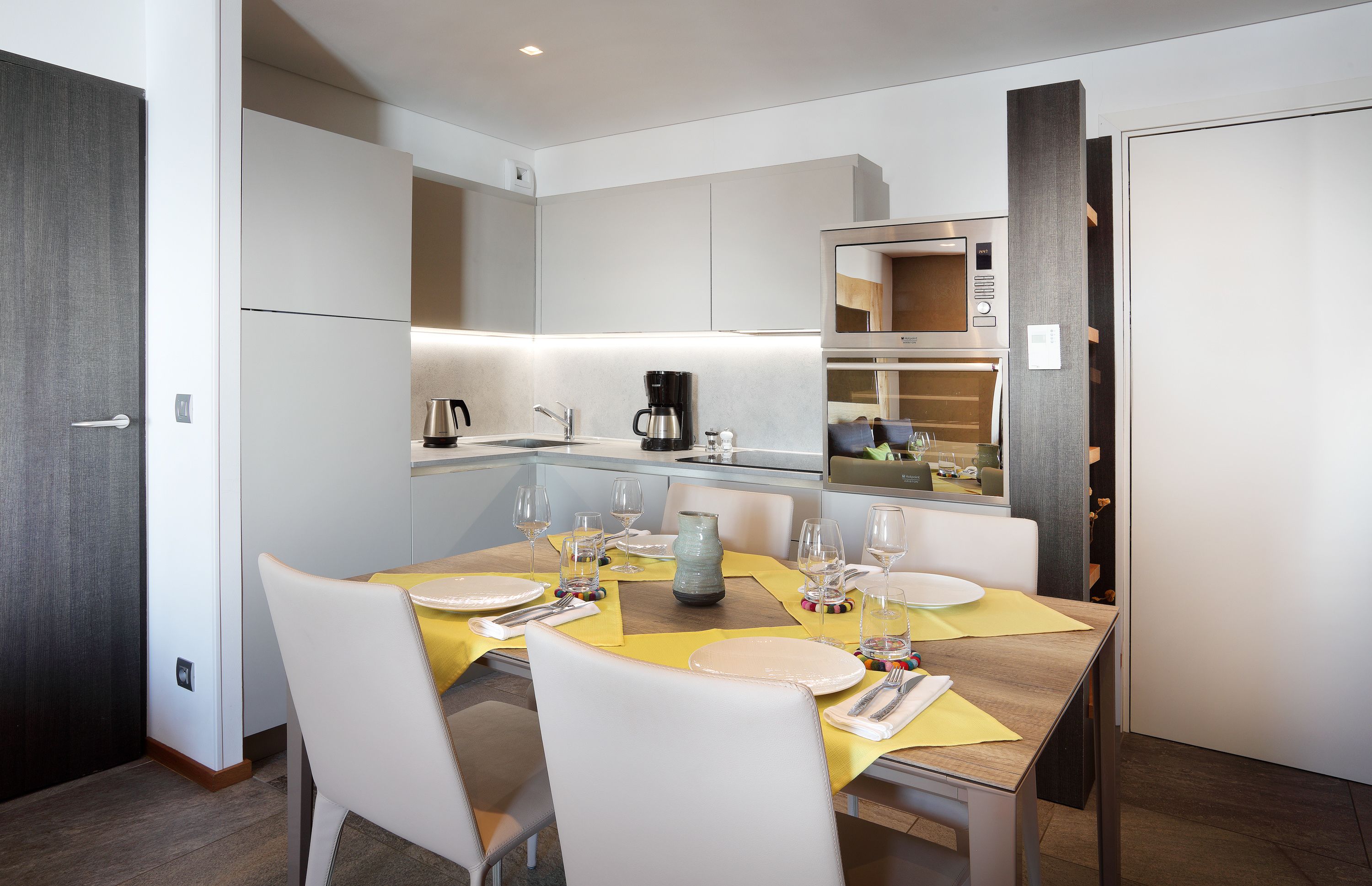 A modern kitchen with white cabinets, a built-in oven, and a coffee maker.