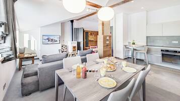 A modern kitchen with a built-in oven and a dining area with a wooden table set for breakfast.