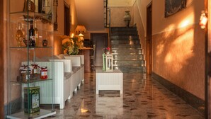 A hallway with a glass display case, wicker furniture, a staircase, and a vase with flowers. - B&B La Mortella (Roccadaspide)