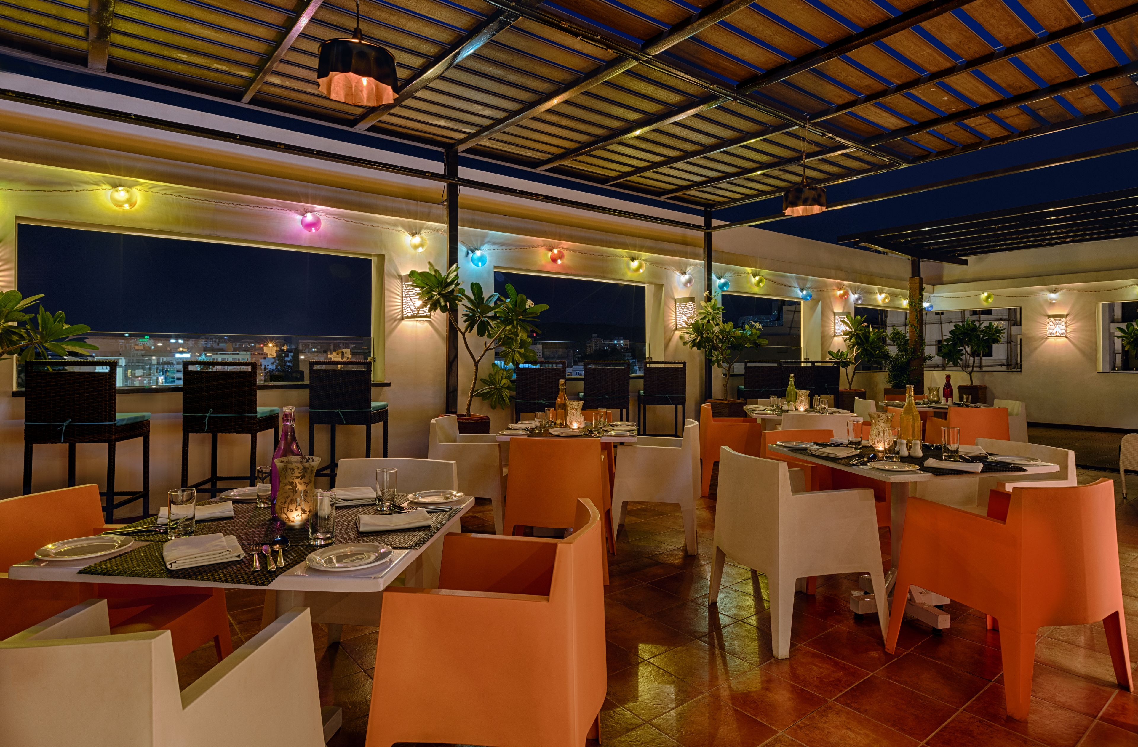 A restaurant with tables set for dining, chairs, and decorative lighting.