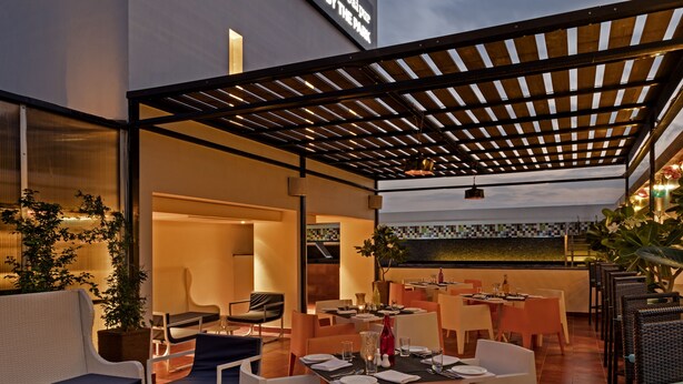 An outdoor dining area with tables and chairs, a pergola, and a sign for 'Zone Bali Park, Jalan By The Park'. - Zone by The Park Bani Park Jaipur (Jaipur)