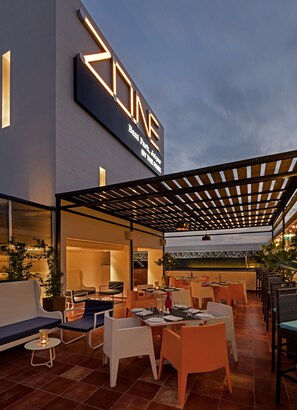 An outdoor dining area with tables and chairs, a pergola, and a sign for 'Zone Bali Park, Jalan By The Park'. - Zone by The Park Bani Park Jaipur (Jaipur)
