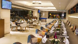 A restaurant with multiple dining tables set for guests, equipped with chairs, and decorated with flowers and napkins. - Zone by The Park Bani Park Jaipur (Jaipur)