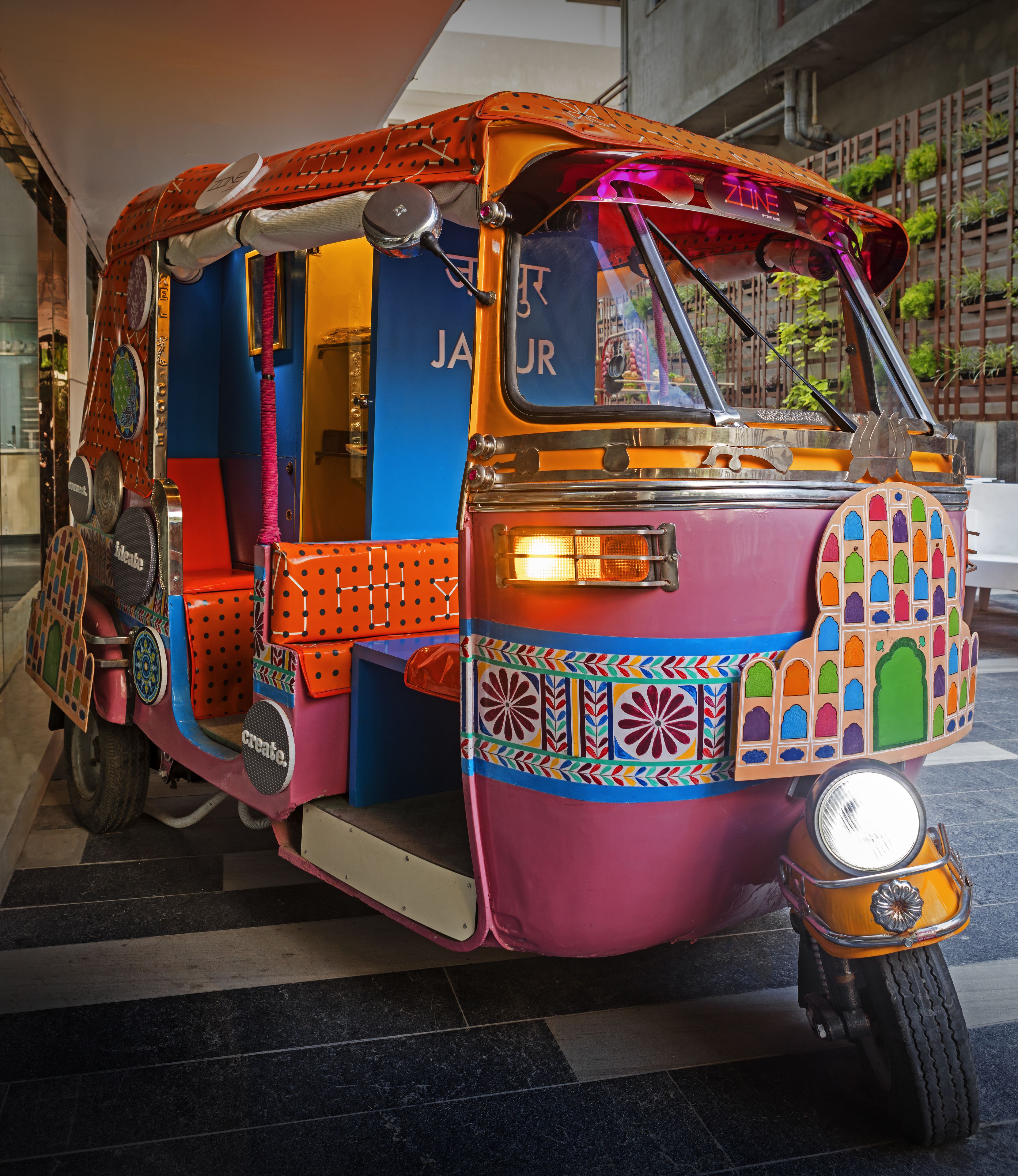 A colorful rickshaw with a vibrant design, a visible door, and a headlight.