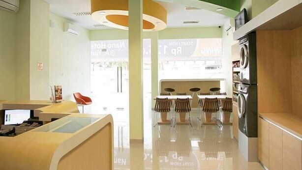 Rebost modern d'hotel amb taulell de recepció, zona de seients i bugaderia a la vista.
