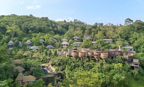 A resort with thatched-roof huts, a swimming pool, and lush greenery.