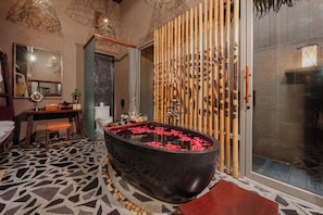 A modern bathroom with a large black bathtub, bamboo decor, and a patterned floor.