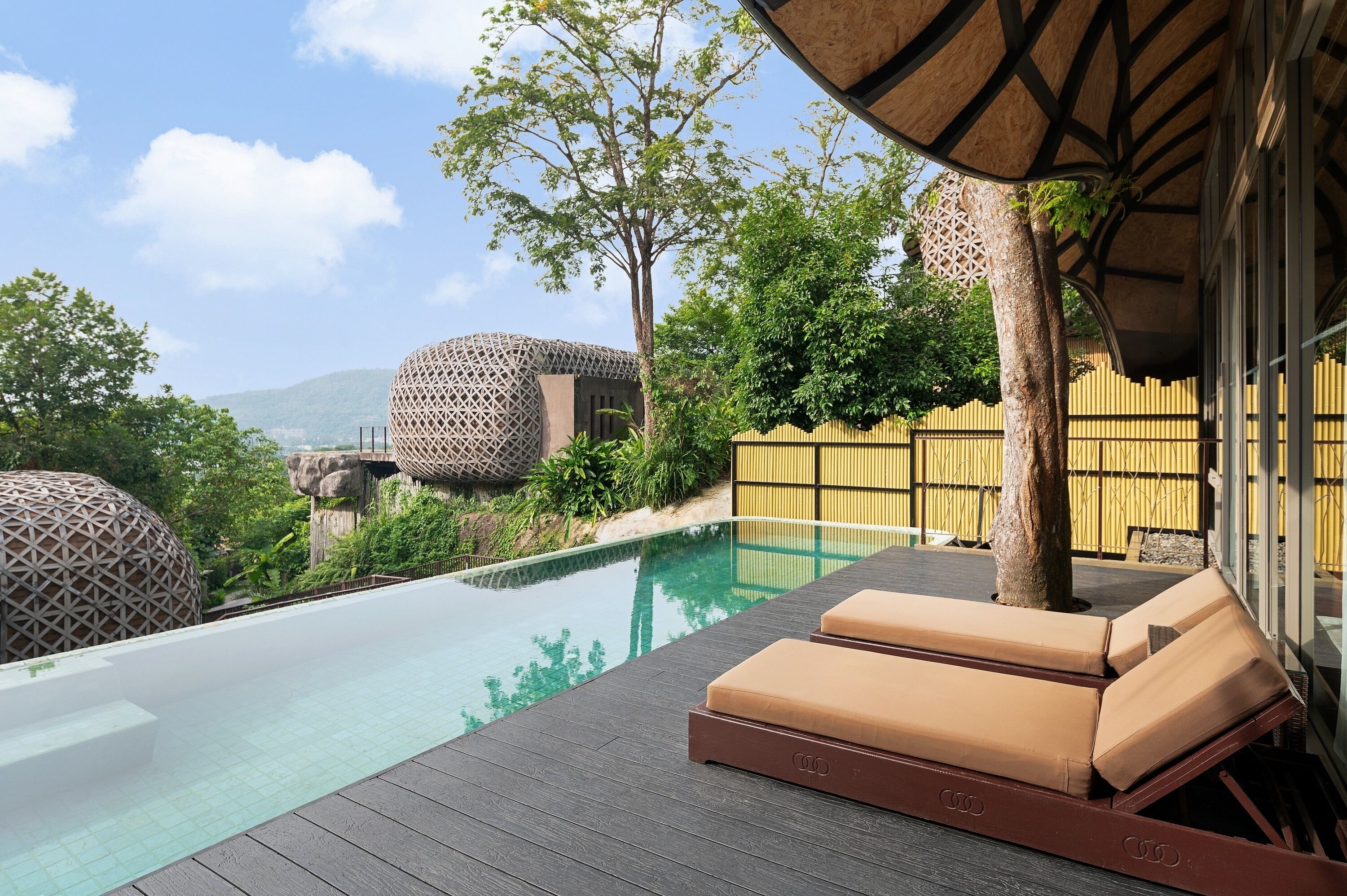Zona junto a la piscina con sillones de descanso, una piscina cristalina y vistas del paisaje circundante.
