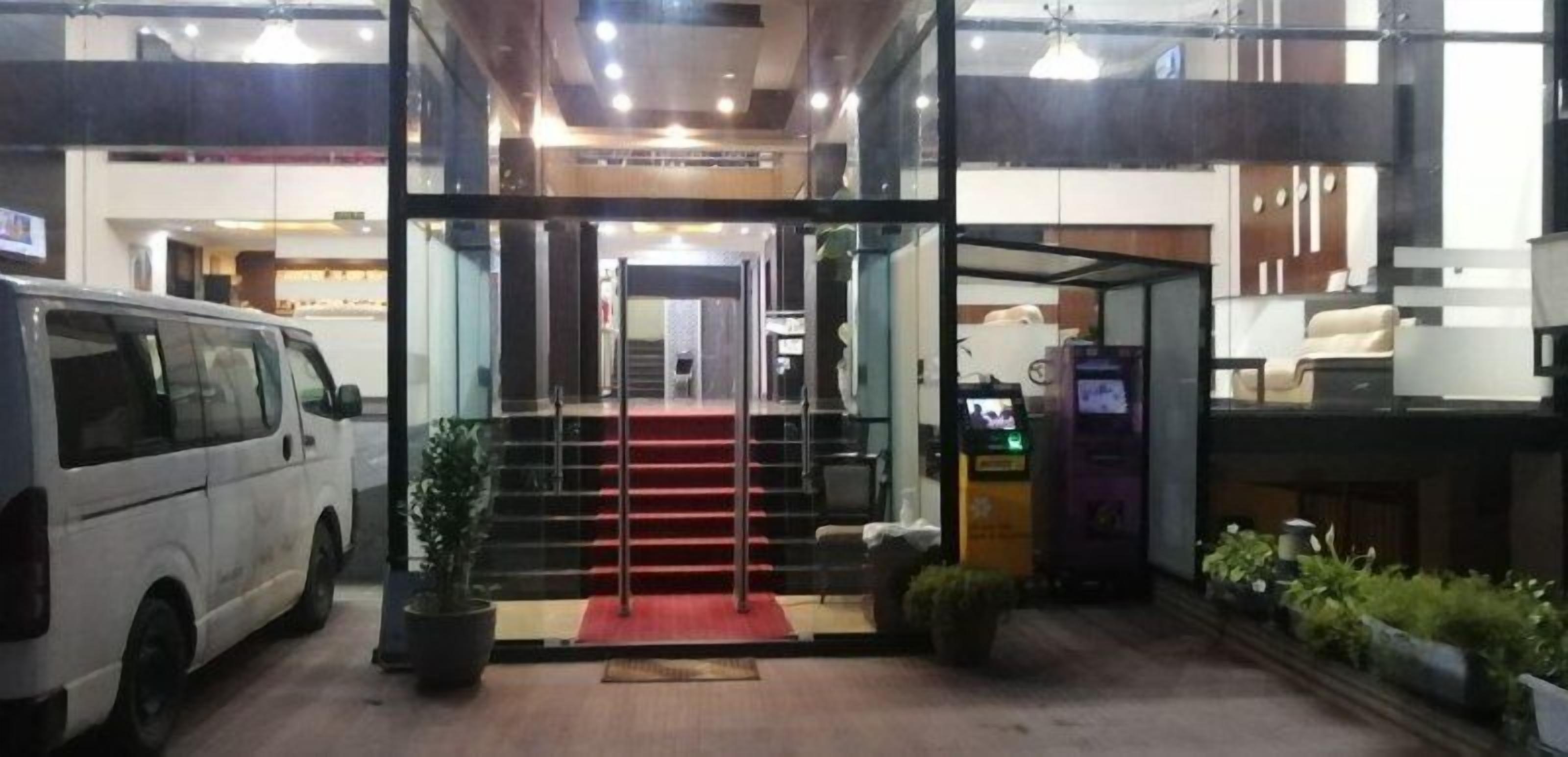 A hotel entrance with a red carpet, a staircase, and a parked van.
