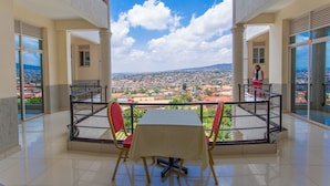 Varanda com mesa e cadeiras, com vista para a paisagem urbana.
