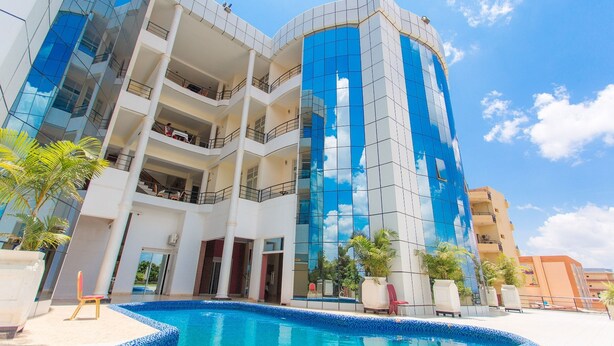 Um hotel moderno com piscina, várias varandas e fachada em vidro refletante.