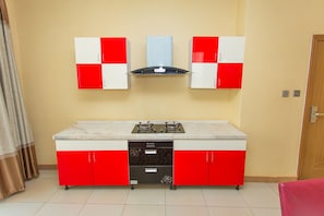A compact kitchen with a gas stove, a built-in oven, and a microwave. - The Mirror Hotel (Kigali)