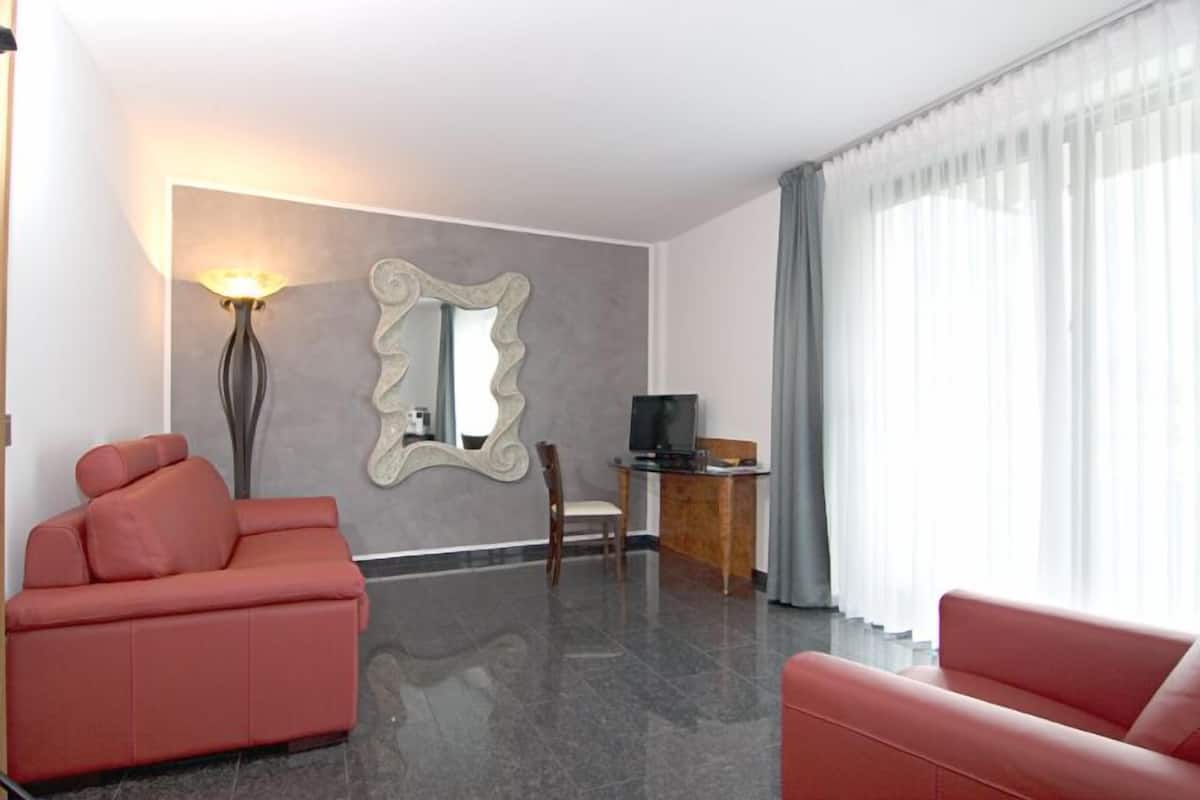 A modern living room with two red sofas, a large mirror, a flat-screen TV, and a wooden side table.