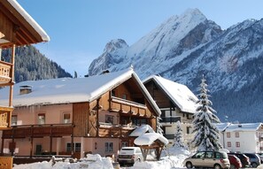 Un chalet en bois doté d’un balcon, entouré de montagnes enneigées et surplombant un ciel dégagé.