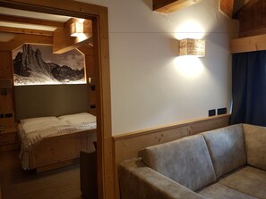 Une pièce confortable avec un lit, un canapé, un plafond en bois et un luminaire fixé au mur.