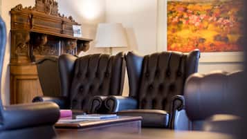Una habitación con dos sillones de cuero negro, un aparador de madera y un cuadro en la pared.