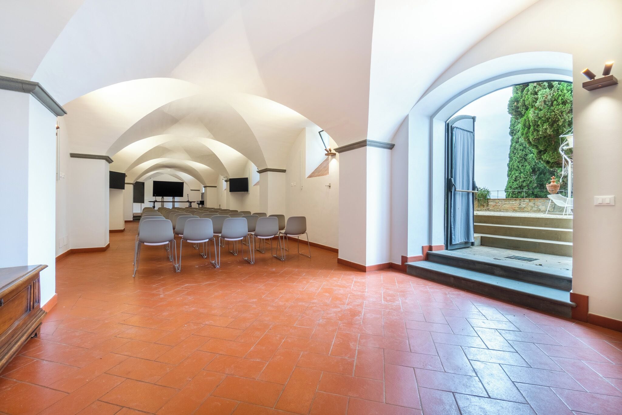 A spacious hall with arched ceilings, a tiled floor, and a seating area with chairs.