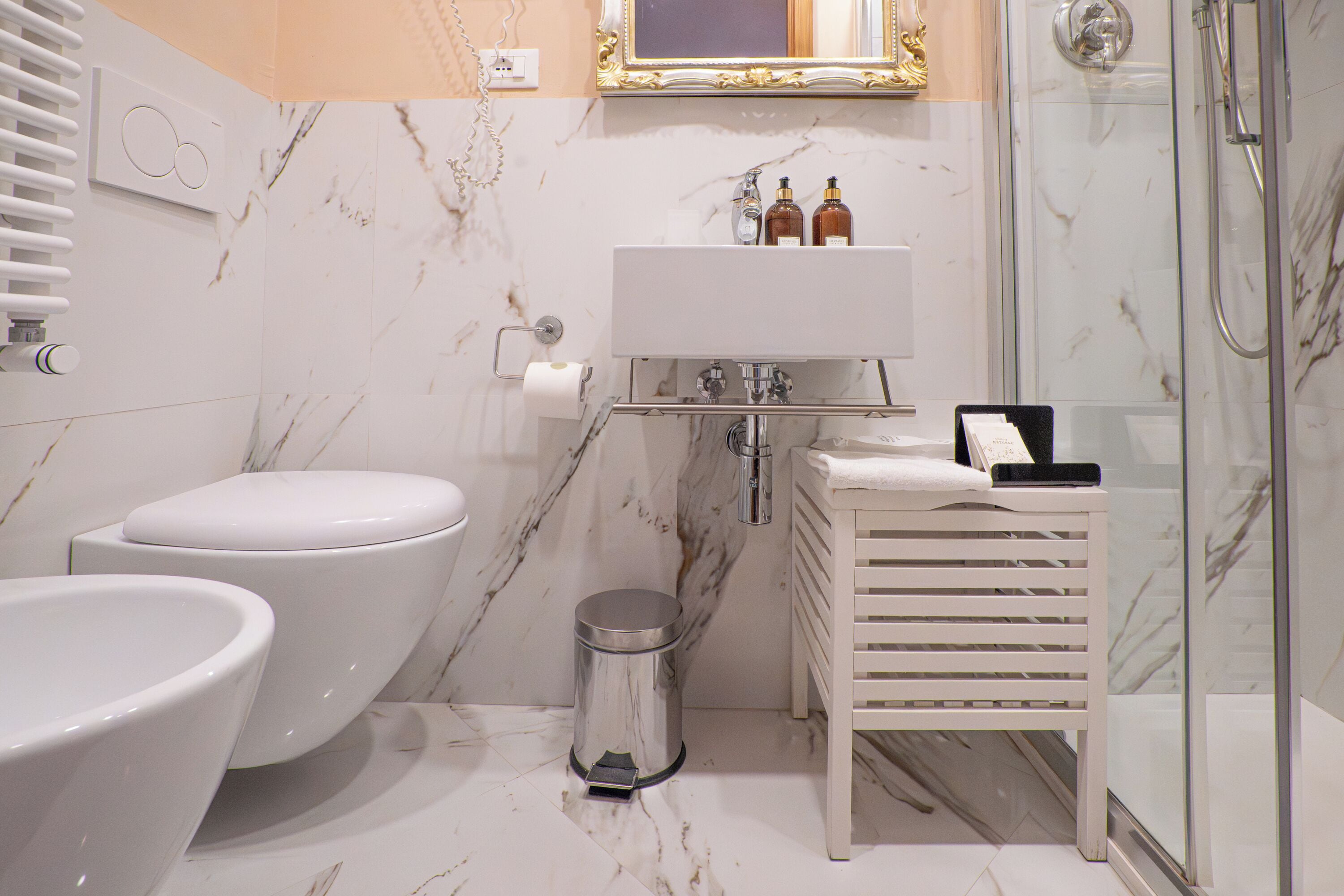 A bathroom with a toilet, bidet, sink, and a glass shower enclosure.