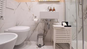 Un baño con inodoro, bidé, lavabo y cabina de ducha de vidrio.