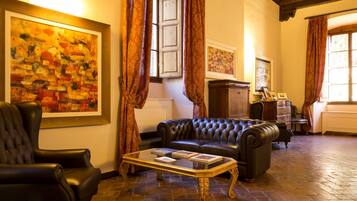 Une pièce avec un canapé en cuir noir, une table basse en verre et un grand tableau encadré accroché au mur.