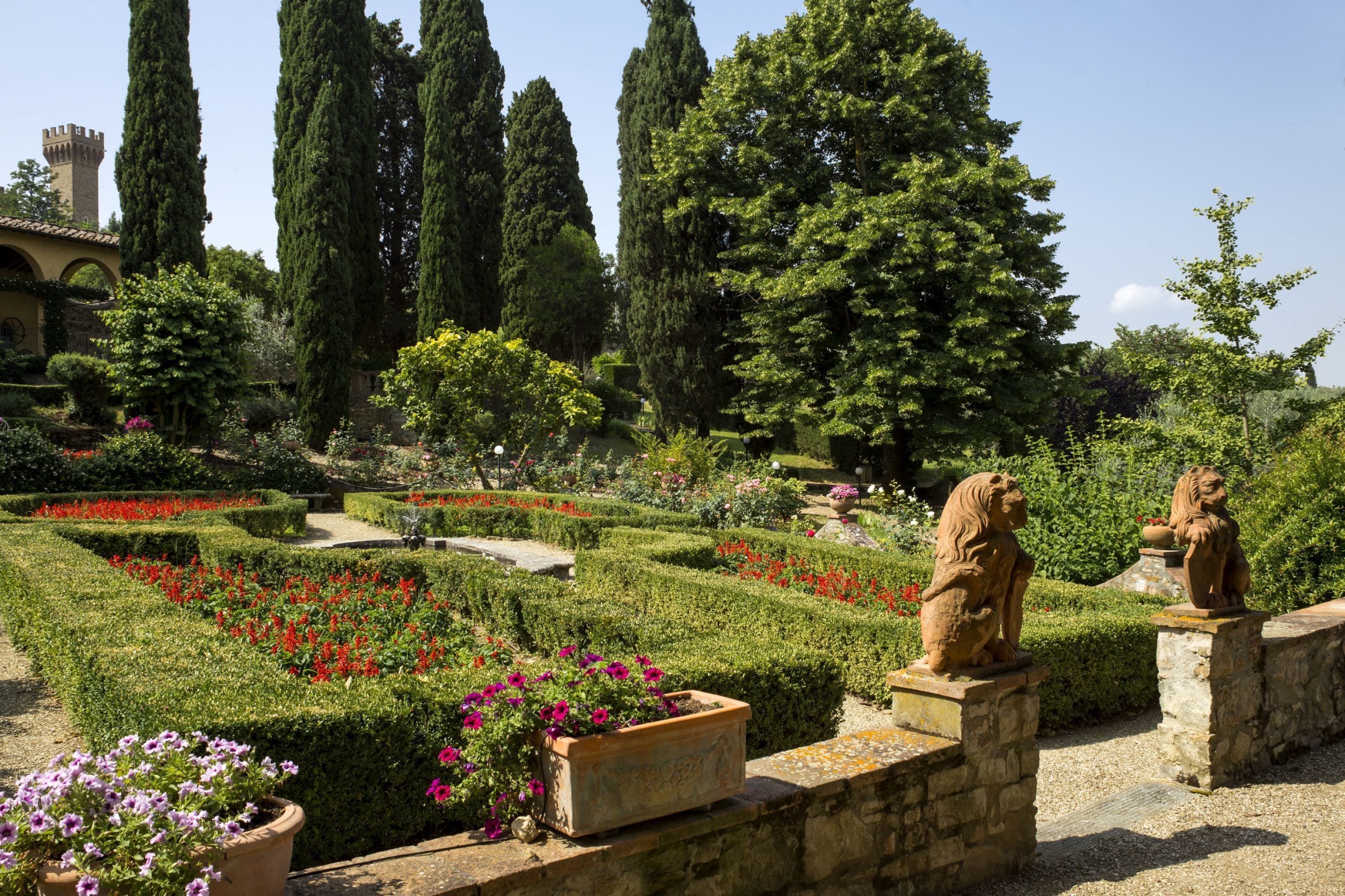 Un jardín cuidado con setos, estatuas y una gran variedad de plantas.