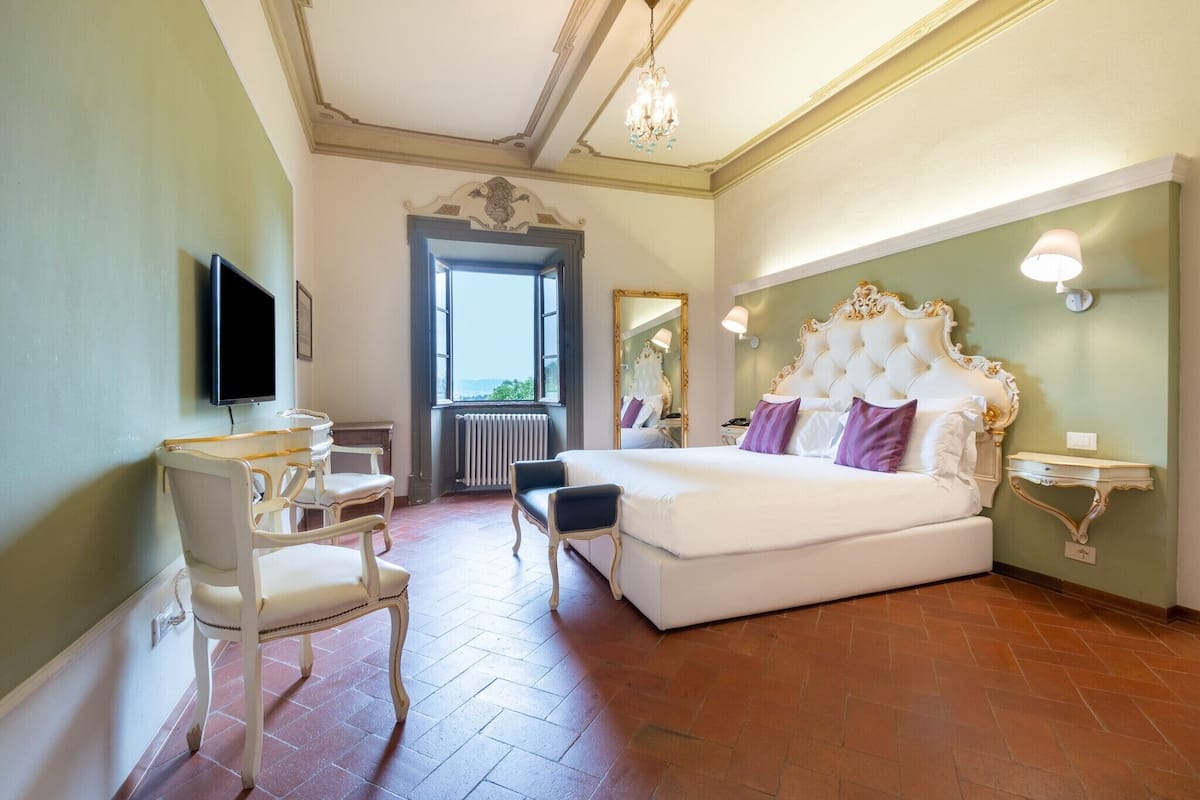 Un dormitorio con una cama grande, un escritorio, una silla, un televisor y vistas al exterior.