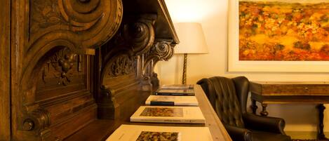 A room with a wooden desk, a chair, and a framed painting on the wall.