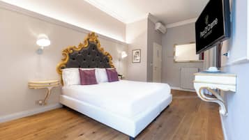 Ein Hotelzimmer mit einem großen Bett, einem Fernseher, einem Nachttisch und einem an der Wand befestigten Spiegel.