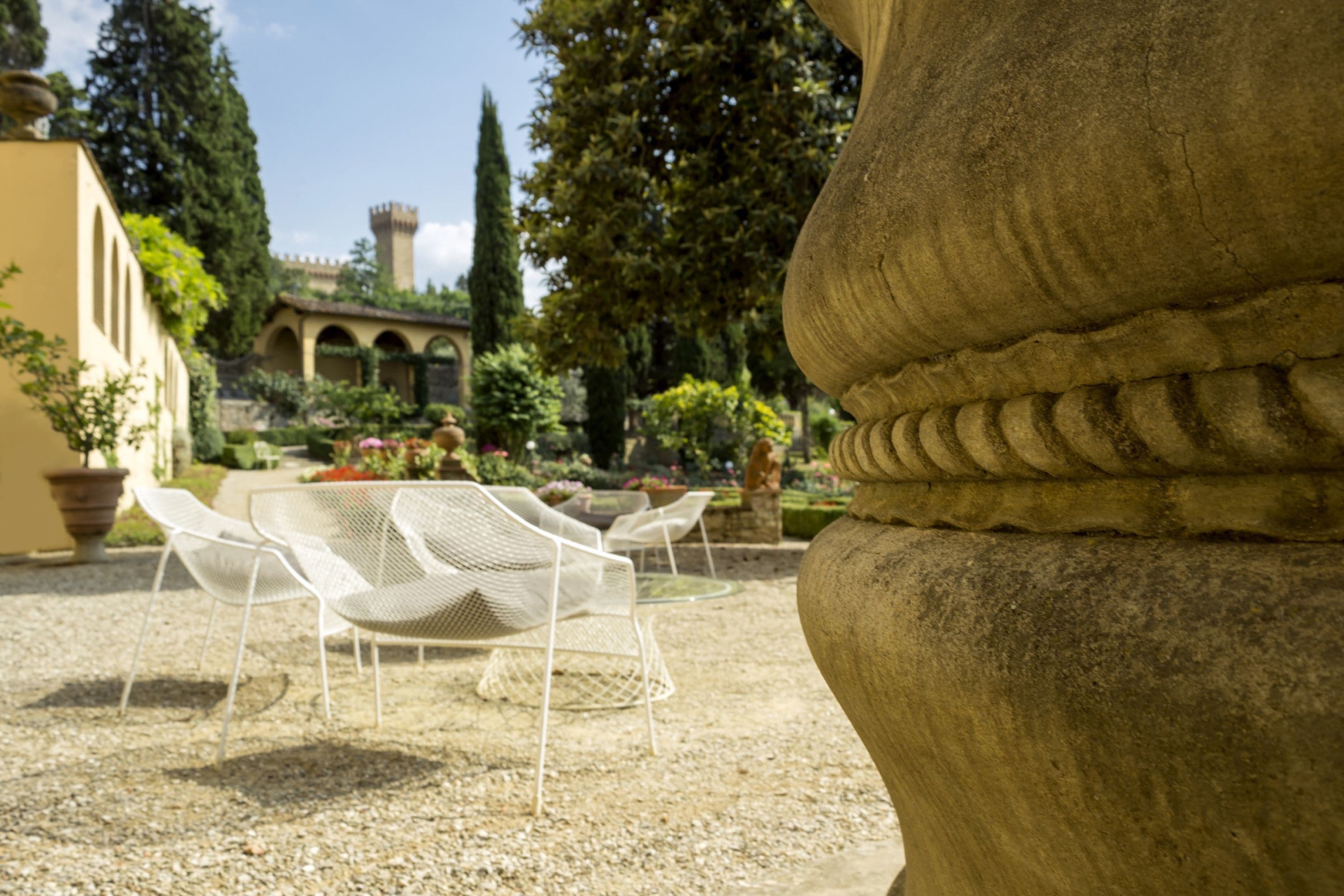 A garden with stone benches and a large vase.