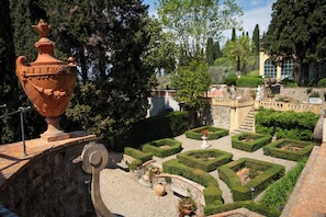 Un patio con una gran urna de terracota, una fuente y setos de formas geométricas.