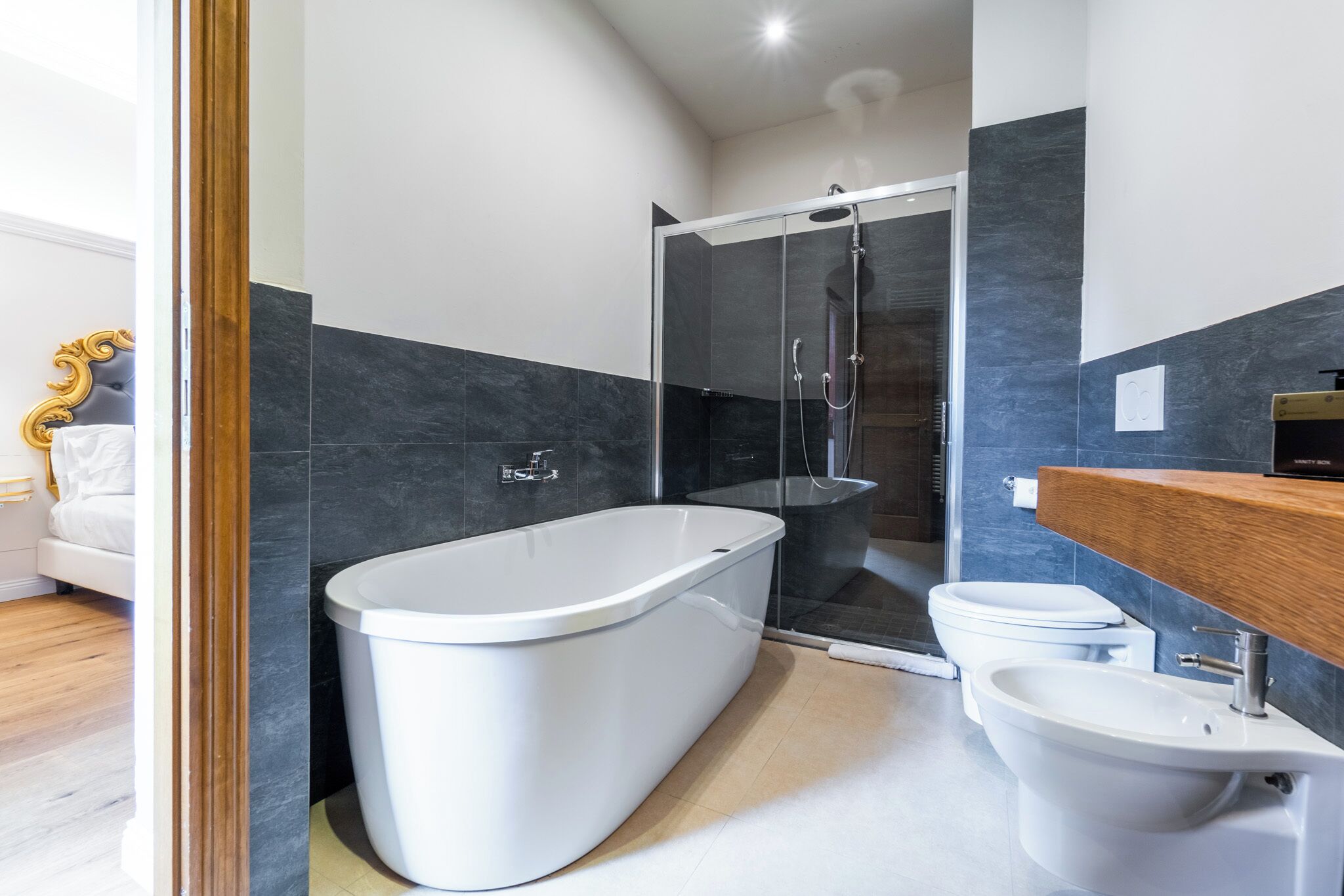 A modern bathroom with a freestanding bathtub, a glass-enclosed shower, a toilet, and a bidet.