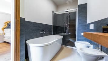 A modern bathroom with a freestanding bathtub, a glass-enclosed shower, a toilet, and a bidet.
