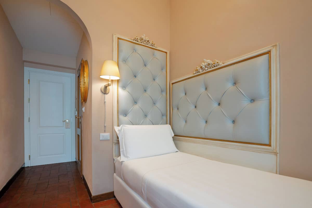 Una habitación de hotel con una cama, una lámpara de pared y una puerta.
