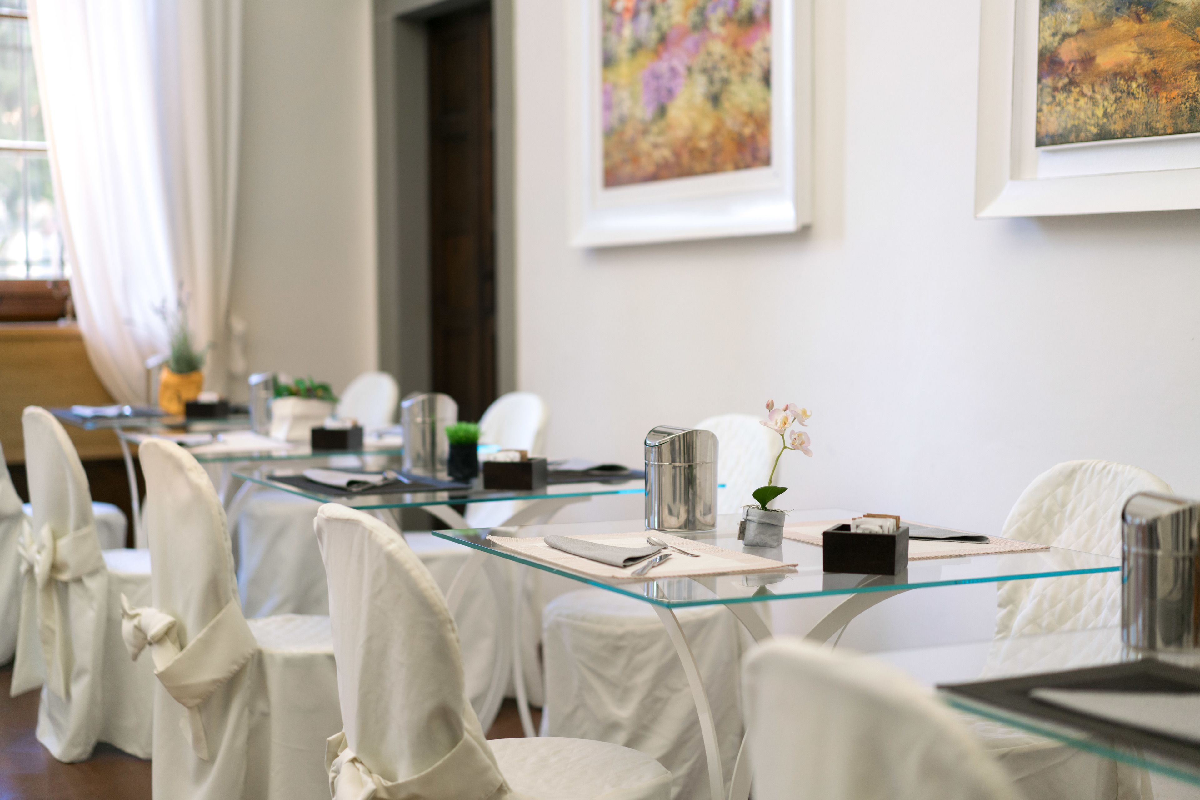 Un salón de conferencias con mesas de vidrio y sillas blancas, cada una con una servilleta y un bolígrafo.