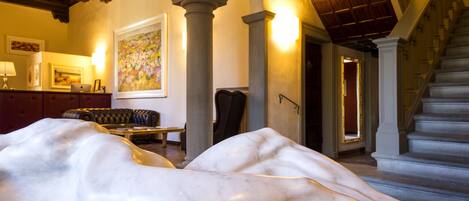 A spacious room with a marble floor, a staircase, and a large painting on the wall.