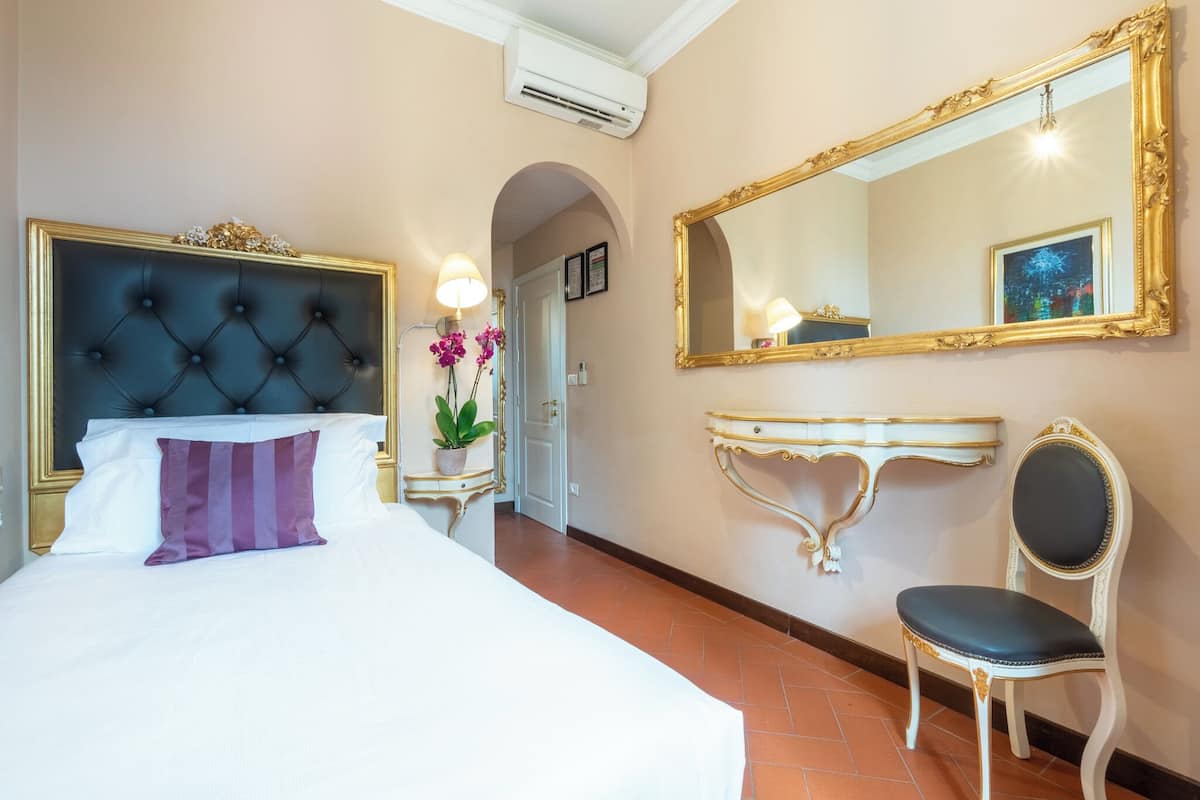 Una habitación de hotel con una cama grande, una tocador con espejo y una silla.