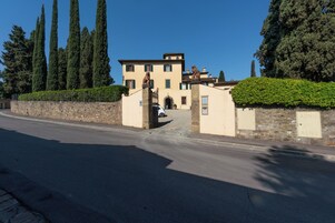 A two-story building with a stone facade, a gated entrance, and a car parked in front.