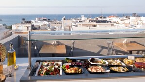 Un buffet con diversi piatti e una bottiglia d'olio d'oliva su un tavolo con una barriera in vetro.