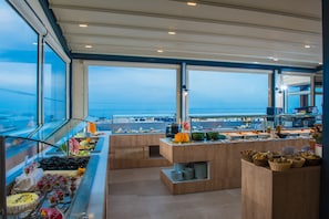 A buffet area with a view of the ocean, featuring various food items and a modern design.