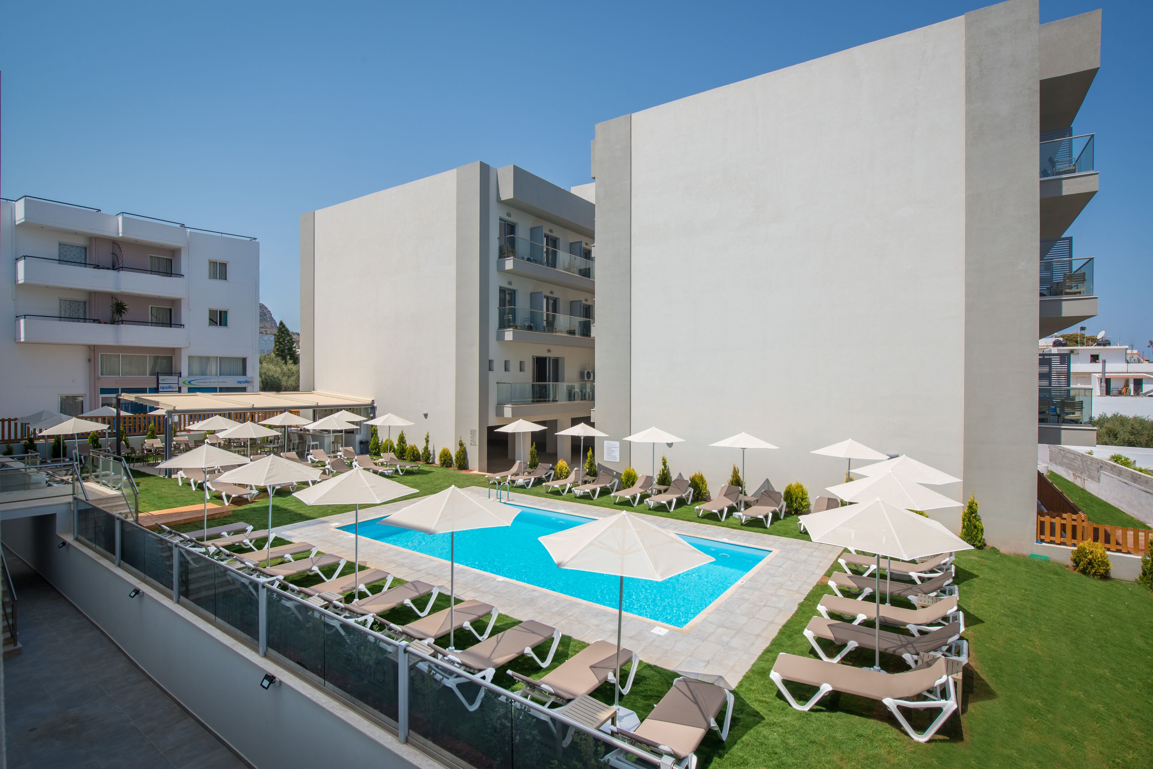 Un espace piscine aménagé sur le toit, avec des chaises longues et des parasols, entouré d’immeubles modernes.
