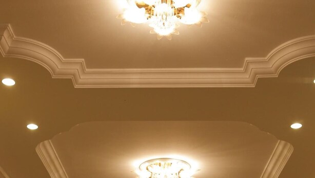 Un vestíbulo de hotel con candelabro, chimenea y mostrador de recepción.