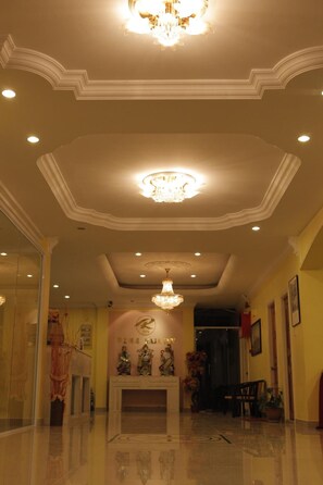 A hotel lobby with a chandelier, a fireplace, and a reception desk.