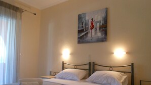 A hotel room with a bed, two bedside tables, a painting on the wall, and a window with curtains. - Ziogas Apartments (Corfu)