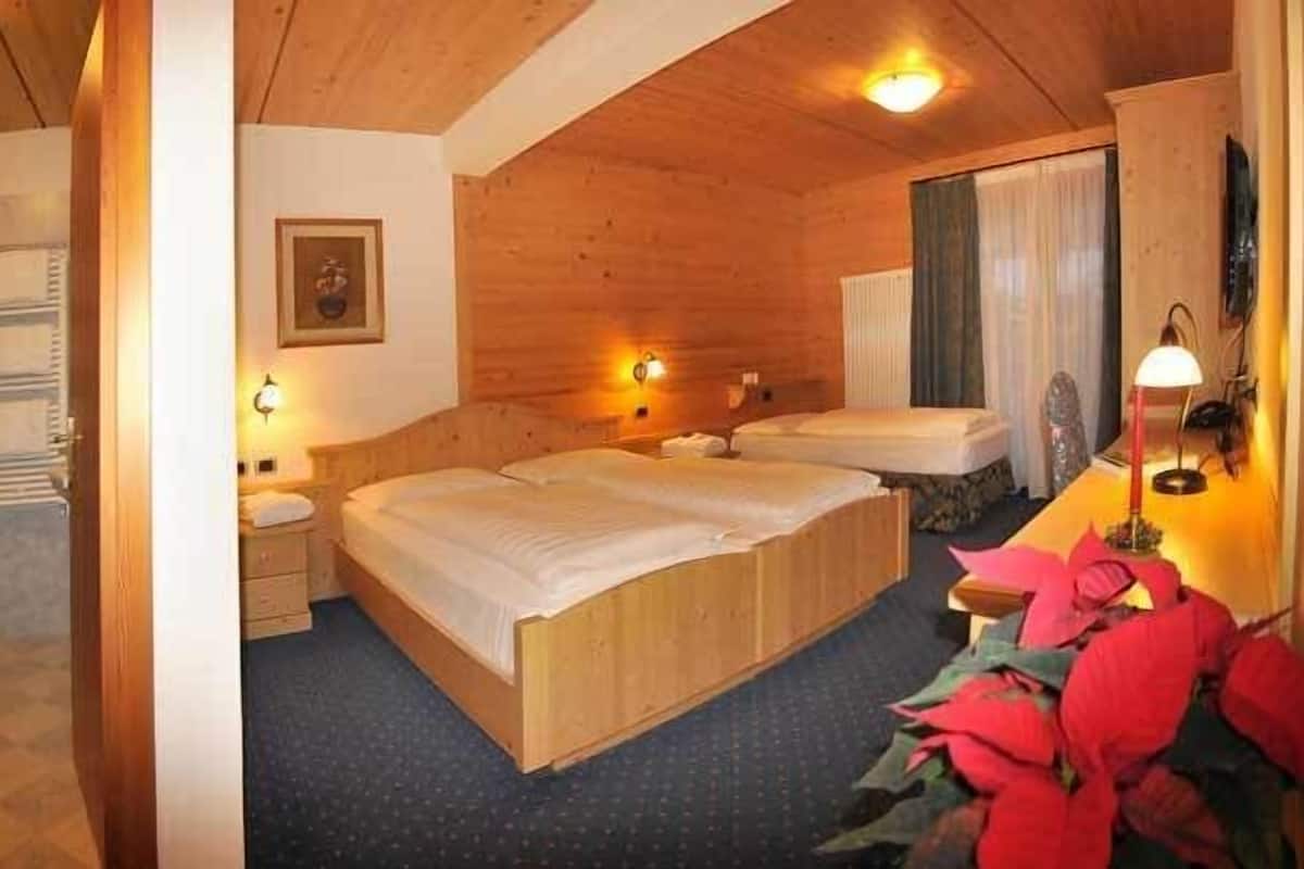 A wooden cabin-style bedroom with two beds, a bathroom, and a small sitting area.