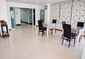 A conference room with a table and chairs, a clock on the wall, and a butterfly-patterned curtain. - Udoncabana (Udon Thani)