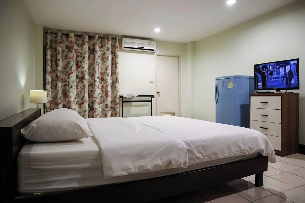 Una habitación de hotel con cama, televisión, armario y aire acondicionado.